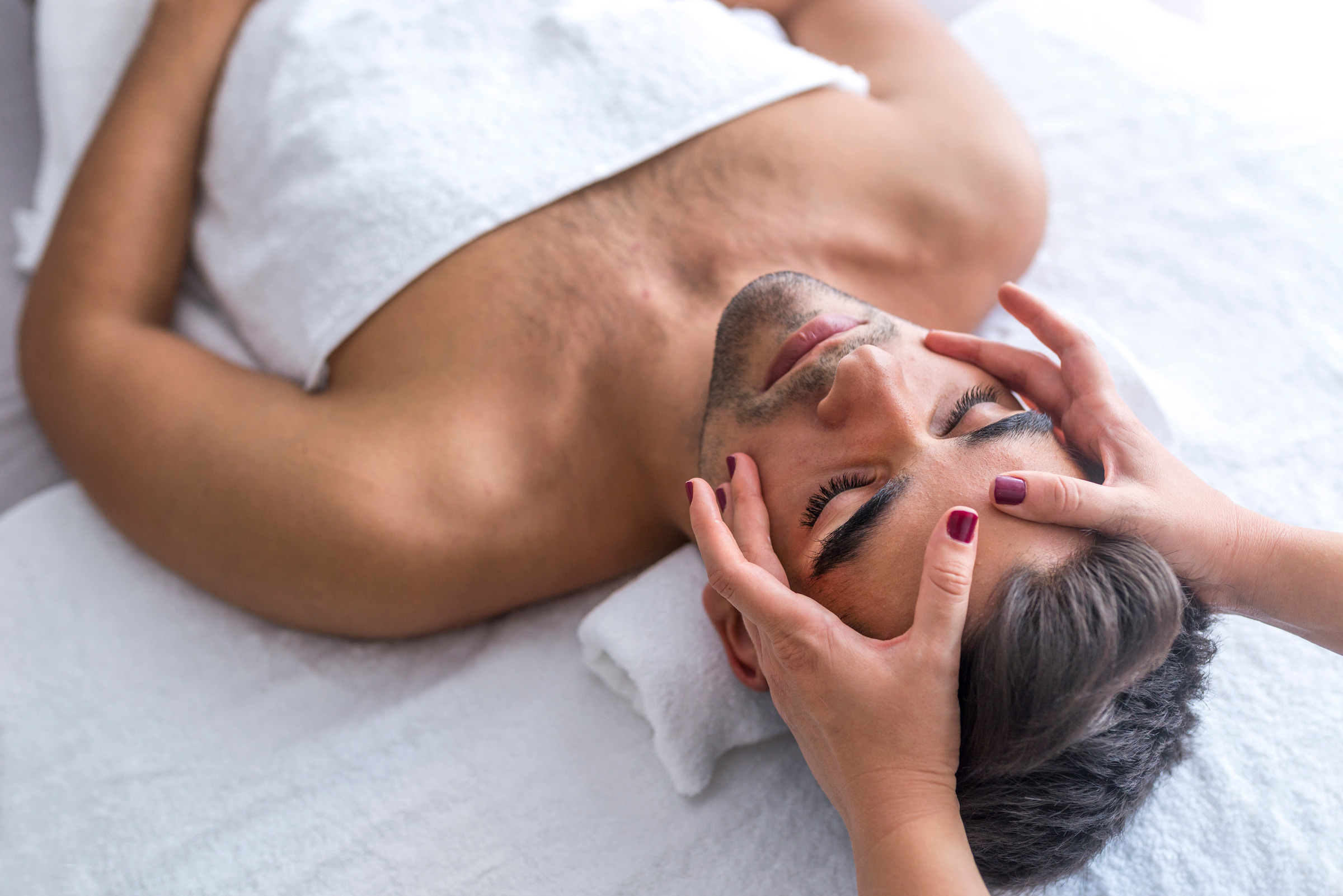 Male beauty - man receiving facial massage at luxury spa
